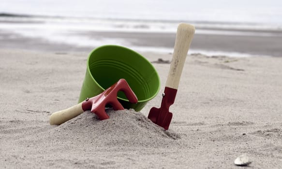 red and green shovel and bucket on the beach