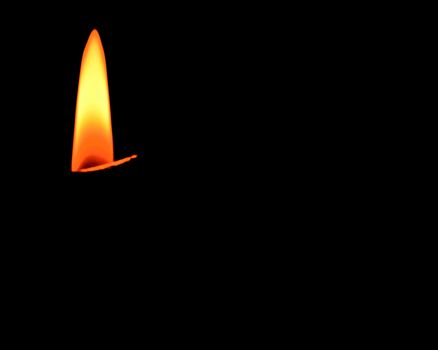 Candle Flame burning against a black background for copy space.