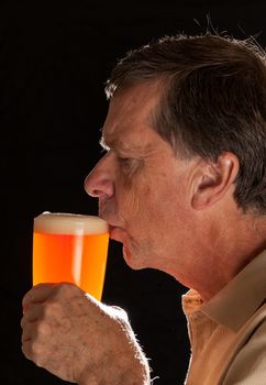 Senior caucasian man in profile drinking from a pint glass of beer or lager