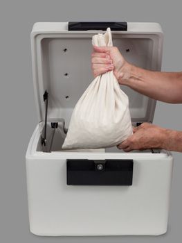 Fire proof safe open and large cotton cash bag being placed inside
