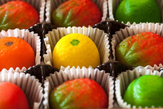 Fruit shaped candies in macro image of marzipan sweets in paper wrappings