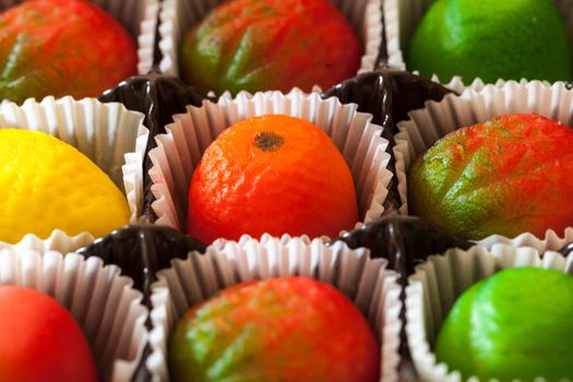 Fruit shaped candies in macro image of marzipan sweets in paper wrappings