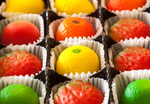 Fruit shaped candies in macro image of marzipan sweets in paper wrappings