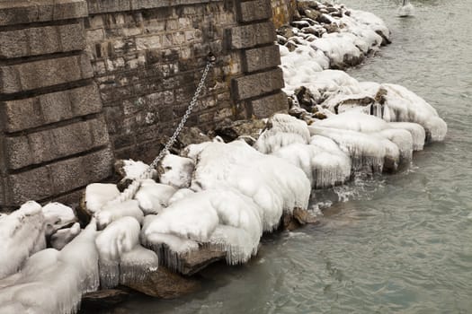 Heavy winter weather deposits ice on rocks on the water's edge