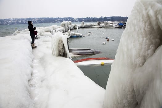 Person surveying icy landscape by lake