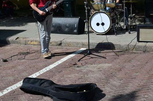 Street music day and musician plays guitar. Attempt to earn on their creations in public place.