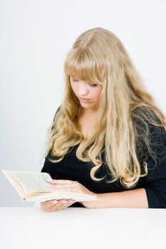 A girl with beautiful long blond hair reading a book