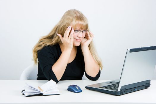 Smiling blonde looks at the monitor laptop