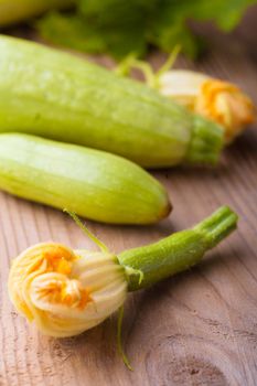 Courgettes with flowers on the wooden background