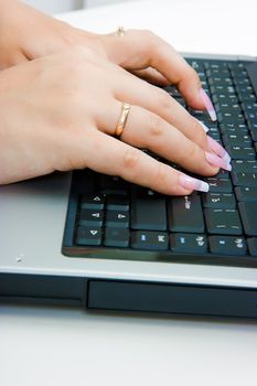 Women's hands with long nails on the laptop keyboard