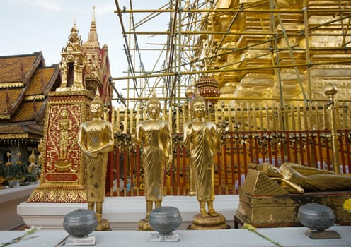 gold buddha images in front of golden temple being reconstructed
