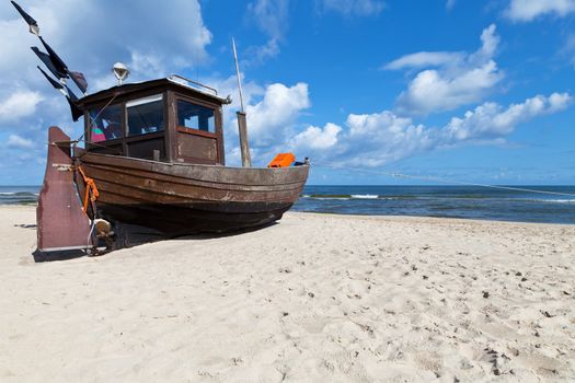 Old fishing boat on a sandy beach in sunny day