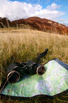 An image of binoculars and map on grass