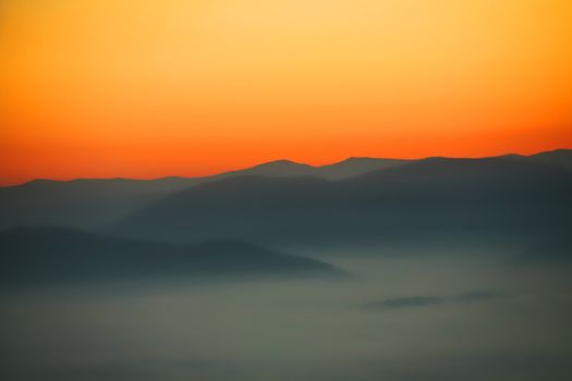 An image of a sunrise in mountains. Mist in a valley