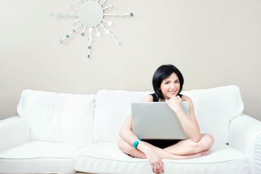 Pretty girl on white sofa with laptop at home