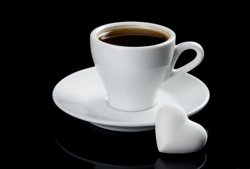 Cup of coffee with heart shape cookie. Isolated on black background