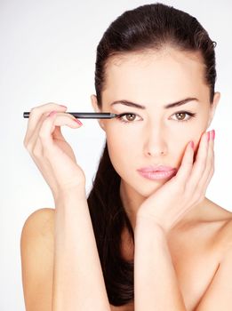 pretty woman applying cosmetic pencil on eye