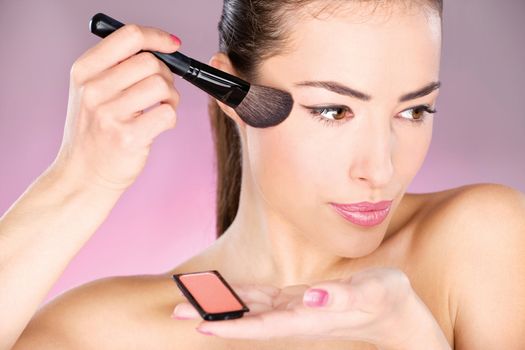 pretty woman applying cosmetic powder brush