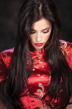 pretty woman in red Cheongsam on dark background