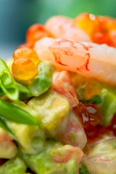Salad of shrimps, avocado and herbs served with soft caviar. Macro, small depth of field. Blurry background.