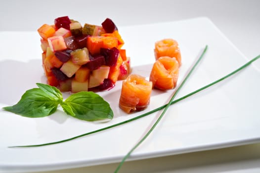 Appetizer of Vinaigrette salad with boiled vegetables and salmon fillet. Small Depth of Field