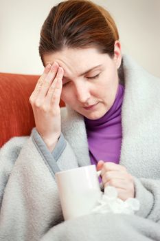 A young sick woman covered with blanket at home