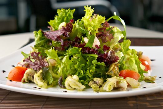 Healthy Seafood Salad with shrimps,octopus, mussels and cherry tomatoes. Indoor. Blurry background of restaurant interior