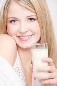 Close up of a pretty blond girl with blue eyes holding glass of milk