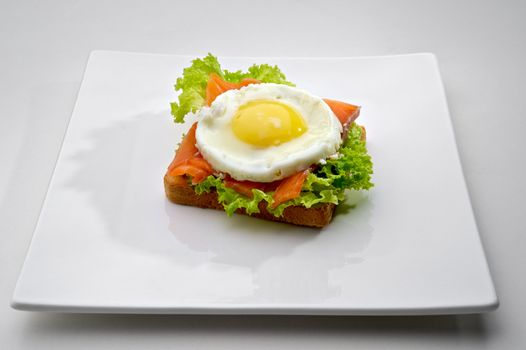 Fish breakfast with scrambled eggs and smoked salmon on toast, served on white plate