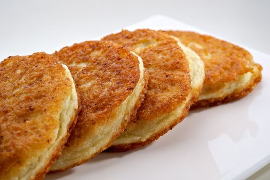 Potato pancakes served on white plate with sour cream