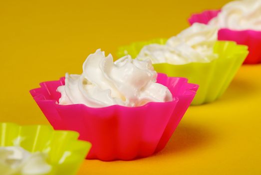 Four portions of whipped cream over yellow background. Shallow DOFÓ