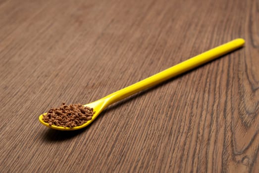 Teaspoon full of chocolate shavings, on a wooden background closeup