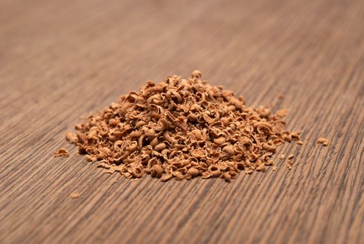 Dark chocolate shavings on a wooden background. Shallow DOF