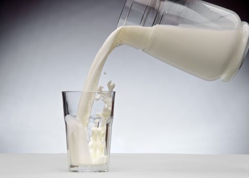 Pouring a glass of milk with splash from jug 