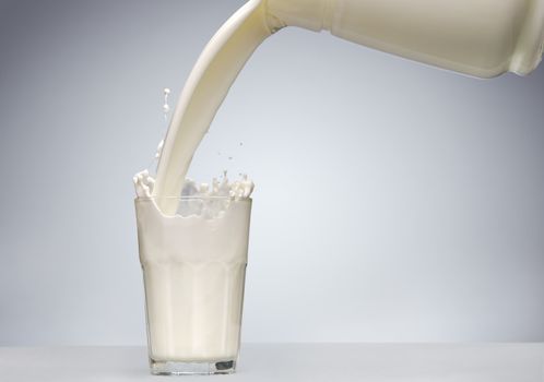 Pouring a glass of milk with splash from jug 