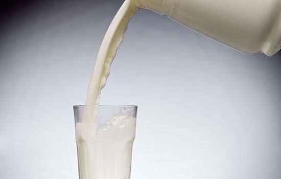 Pouring a glass of milk with splash from jug 