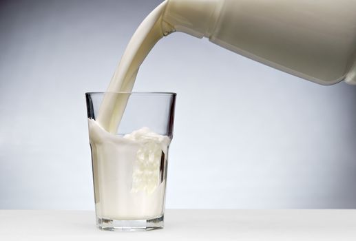 Pouring a glass of milk with splash from jug 