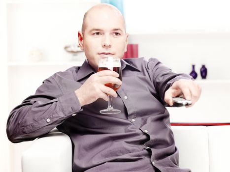 man at home drinking beer and change channels on television