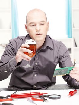 man at home sipping a beer and think about how to repair an electronic device