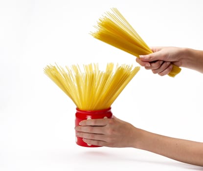 Woman's hands holding red jar full of spaghetti inside.  Isolated on a white background.