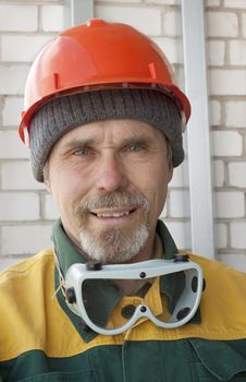 An elderly worker with spectacles and a protective helmet