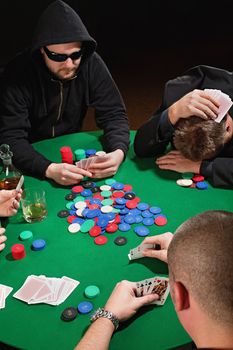 Photo of four men playing poker with one player frustrated. Focus is on the winning poker hand.