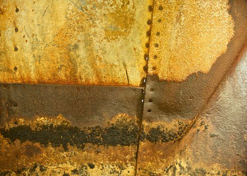 Horizontal background of rusted and grungy metal with visible seams and rivet holes from the side of a naval vessel