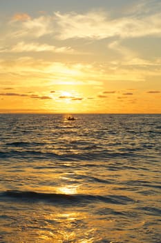 Vertical photo of a small water craft or boat on the waters of the Pacific Ocean at sunset