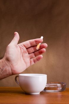 Hand holding a cigarette and a cup ashtray.