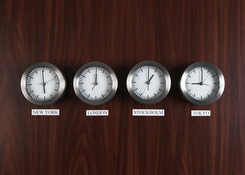 Four clocks with different time on Teak background