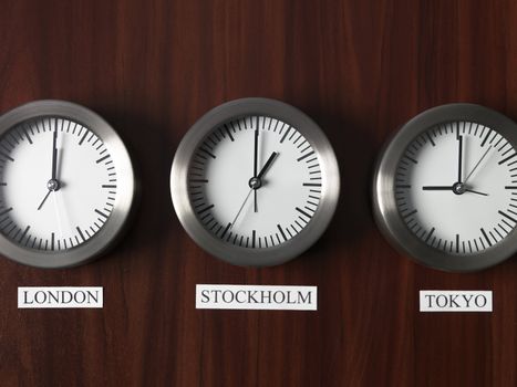 Three clocks with different time on Teak background
