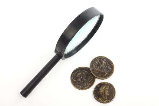 magnifying glass and fake ancient coins over white