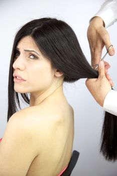 Hairdresser cutting long ponytail of gorgeous female model
