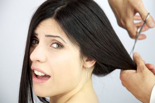 Hairdresser cutting very long hair to a beautiful female model